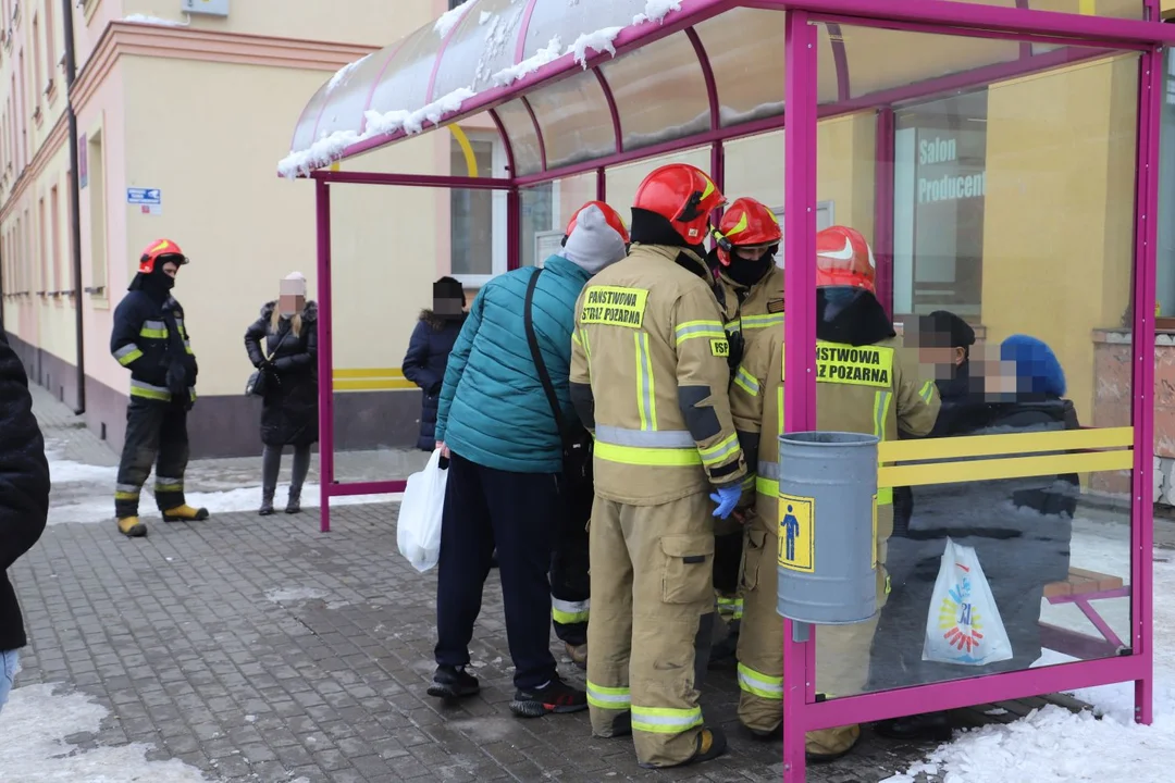 Na przystanku autobusowym w centrum miasta zasłabł starszy mężczyzna, pomagają mu strażacy